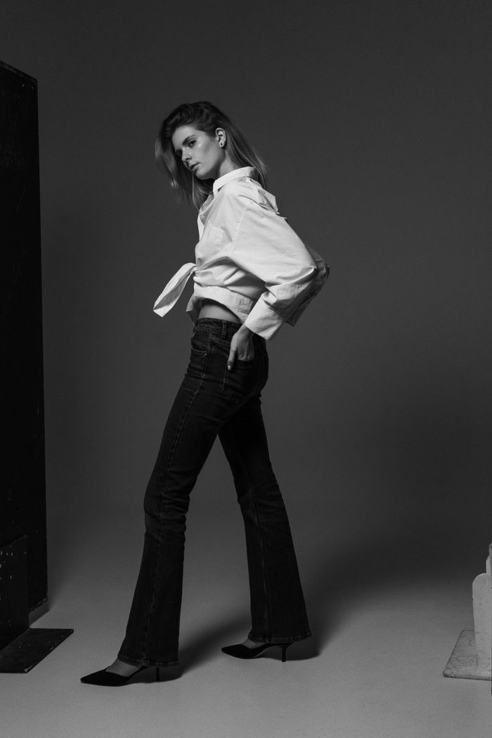 Stylish black and white portrait of a woman posing in jeans and blouse. Elegant and fashionable.